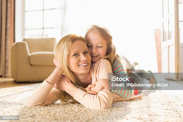 Portrait Of Happy Mother With Daughter Lying On Floor Stock Photo - Download Image Now