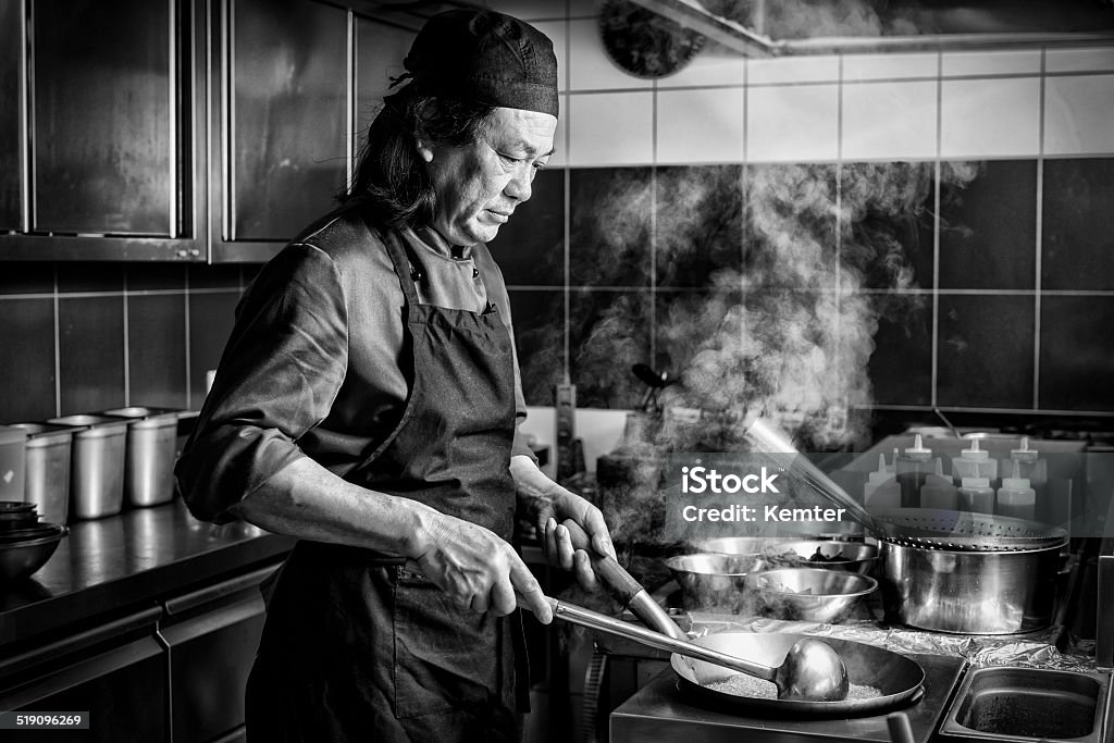 chinese man cooking in asian restaurant serious chinese man cooking in the kitchen of an asian restaurant Chef Stock Photo
