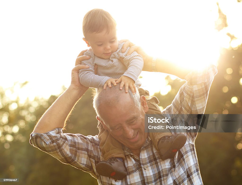 Grandfather and grandson Grandfather carrying grandson on shoulders in park on sunny autumn day Baby - Human Age Stock Photo