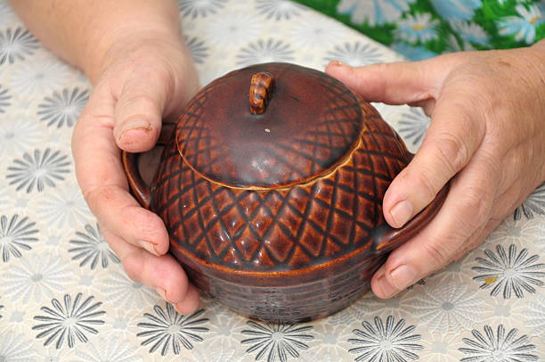 Elderly persons hands holding cooking pot on table