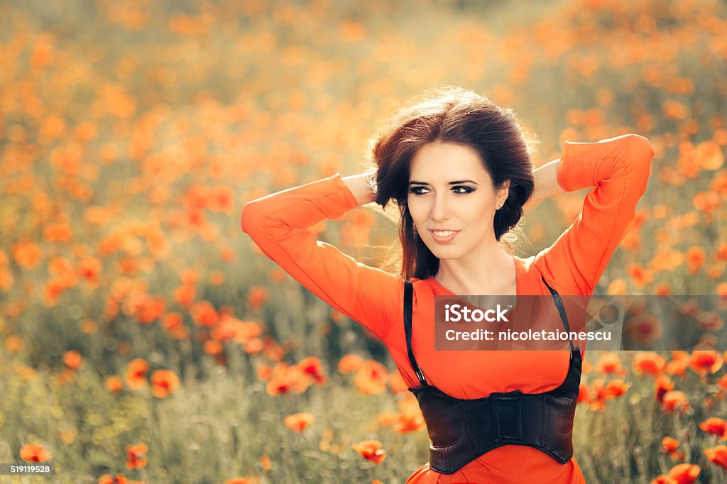 Beautiful Woman in a Field of Poppies Portrait of a happy girl in red chiffon blouse and black corset in summer floral landscape Adult Stock Photo