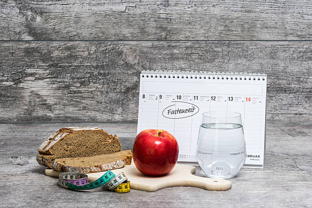 Diet Meal Grey Background with Calendar (Fastenzeit) Diet meal on a grey background with calendar and the german word for Lent "Fastenzeit". lent stock pictures, royalty-free photos & images