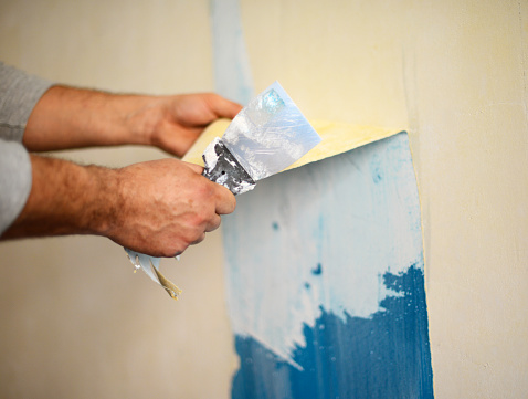 Hands removing wallpaper