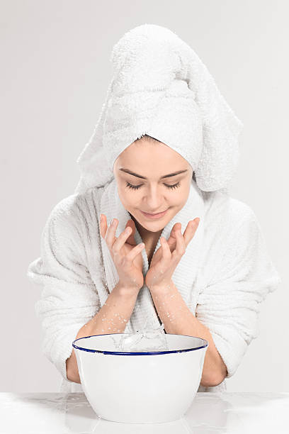 istock Young woman washing face with clean water 519129392