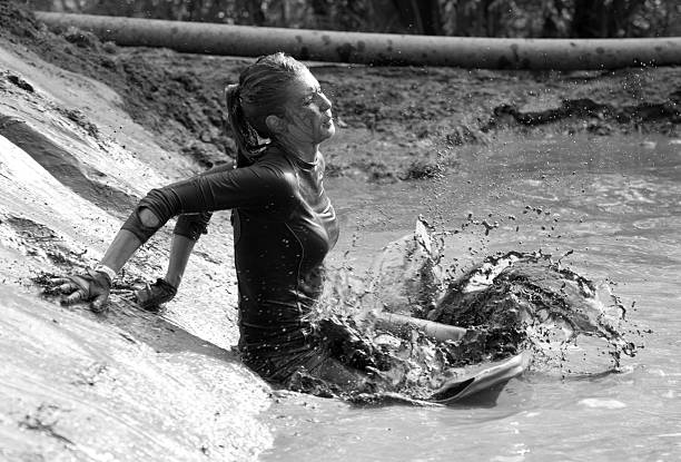 fêmea participante chapinhar na lama no ar livre de acontecimentos - individual event women people autumn imagens e fotografias de stock