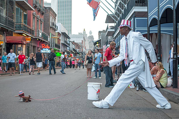 New Orleans, USA - October 10, 2014: Man dressed in white suit and patriotic hat stands frozen in stride on Bourbon Street as if walking a small stuffed dog.