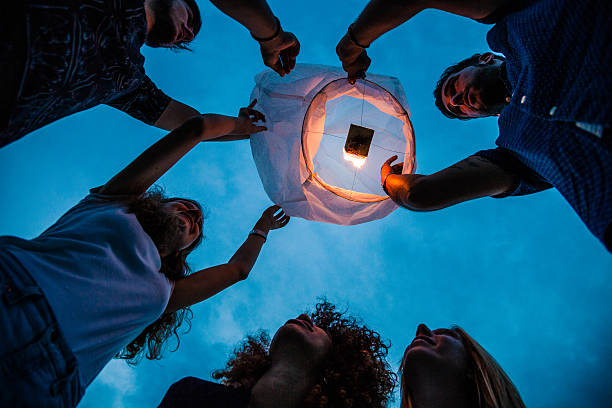 istock Friends lighting up a paper lantern at party 519156842