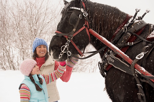Mother and daughter with horse in snow
