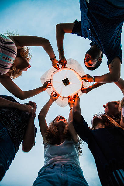 istock Friends lighting up a paper lantern at party 519159190