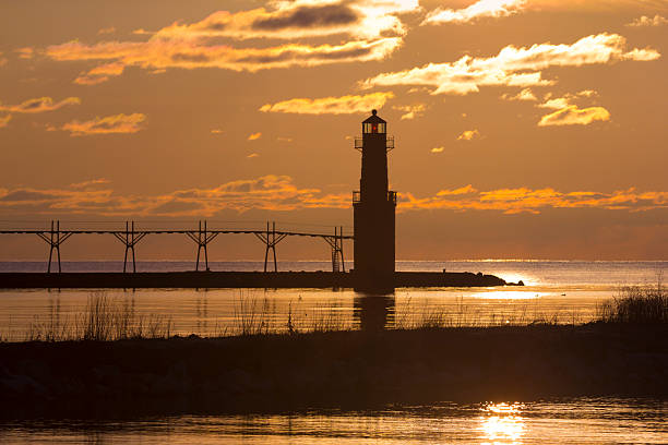 istock Harbor lighthouse silhouetted in golden sunrise 519164052