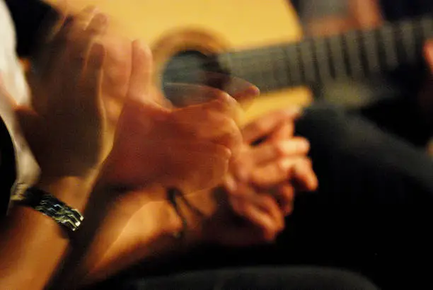 Close up of clapping hands and a guitar during a flamenco dance