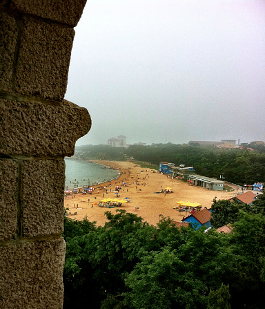 Qingdao Beach, China  - August 10, 2011:This may not rank as Qingdao’s largest or most happening beach, but unlike the rest, it is devoid of hawking vendors: instead it offers a rare atmosphere of pragmatic calm. Wedged between tree-thick hills and Taiping Bay’s clear, lapping waves, this serene setting is perfect for those who seek escape. Even Chairman Mao favored this slice of sand. Nearby, Huiquanjiao Horn offers a fan of trees surrounded walking trails.