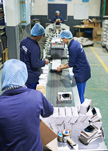 Shot of a people working inside a printing, packaging and distribution factory. The commercial designs displayed in this image represent a simulation of a real product and have been changed or altered enough by our team of retouching and design specialists so that they are free of any copyright infringements