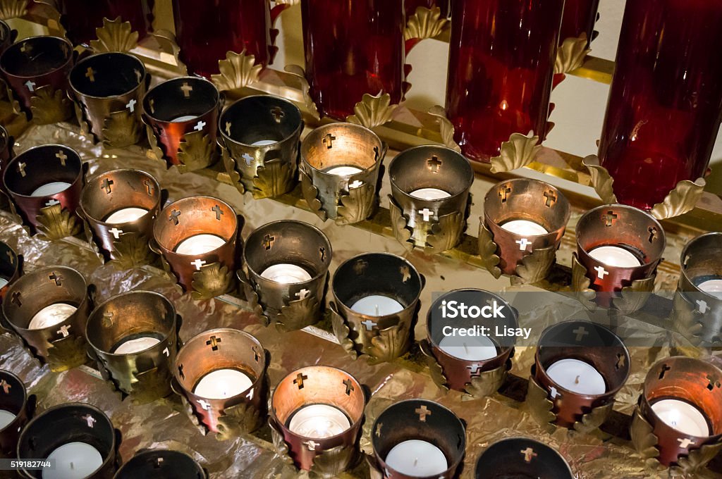 Votive Candles A group of votive remembrance candles lined up and lit in a church. Burning Stock Photo