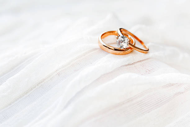 istock Golden wedding rings with diamond lie onwhite fabric. 519182952