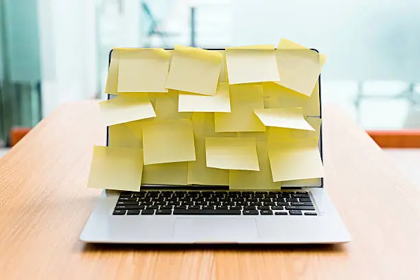 Laptop screen covered by group of yellow adhesive notes