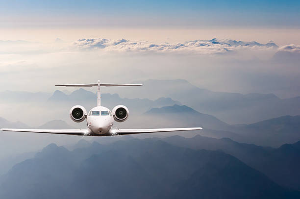 Airplane fly over clouds and Alps mountain on sunset. Front Airplane fly over clouds and Alps mountain on sunset. Front view of a big passenger or cargo aircraft, business jet, airline. Transportation and travel concept. military private stock pictures, royalty-free photos & images