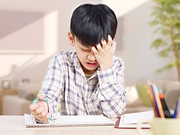 asian child studying at home 10 year-old asian elementary schoolboy appears to be frustrated while doing homework at home. child japanese culture japan asian ethnicity stock pictures, royalty-free photos & images