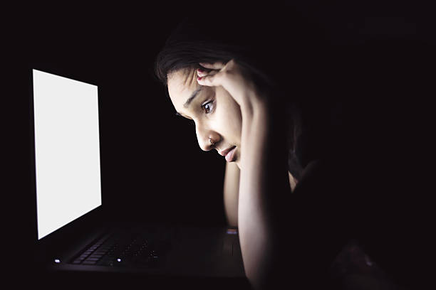 istock Woman in dark room looking at laptop screen 519214300