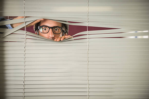 Startled Nerd staring Through Venetian Blinds Nerdy startled man in glasses, mid thirties, staring through Venetian blinds. creepy stalker stock pictures, royalty-free photos & images