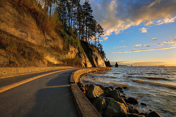 seawall and rock wall at sunset, with famous Siwash Rock in the sea water, Stanley Park, Vancouver, British Columbia, Canada