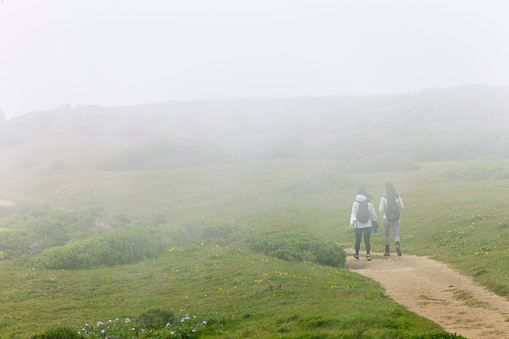 Point Reyes, California, USA - April 2, 2016: Two hikers enjoy the weekend at Tomales Point of Point Reyes National Seashore, California. Low fog on the background.
