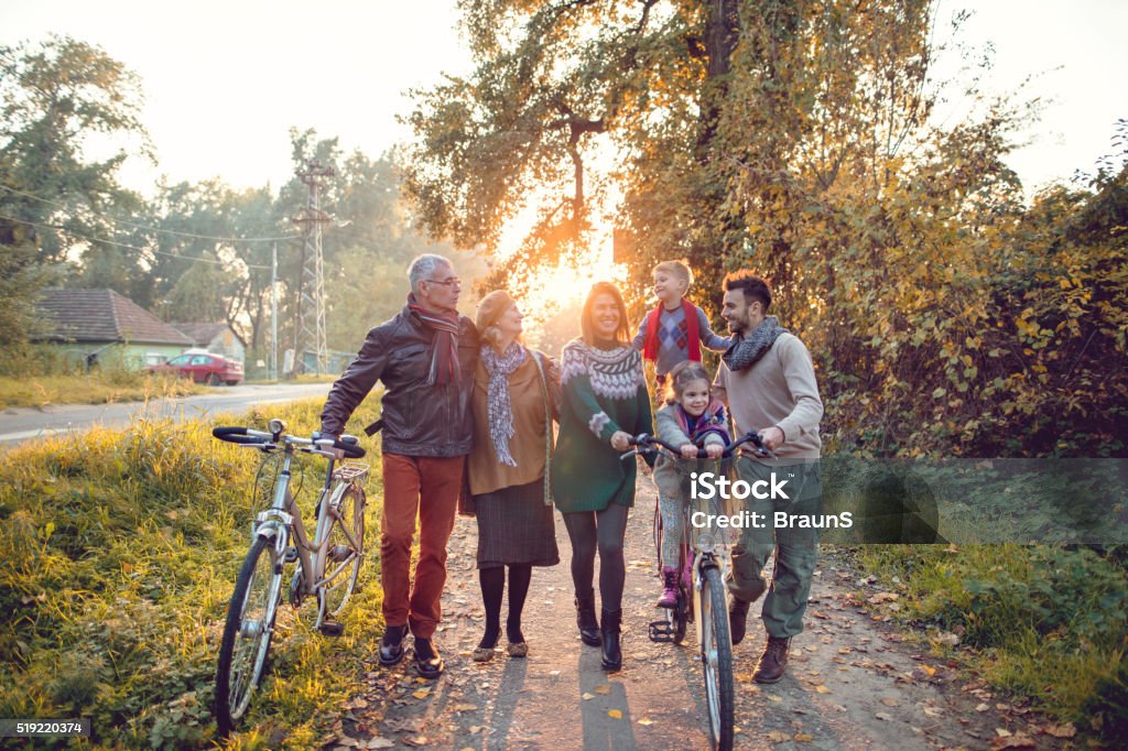 Happy multi-generation family having fun with bikes in autumn da Smiling extended family spending an autumn day in the park while walking with bikes. Autumn Stock Photo