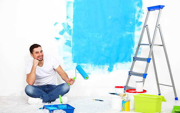 istock happy man doing repairs, paint wall at home 519223050