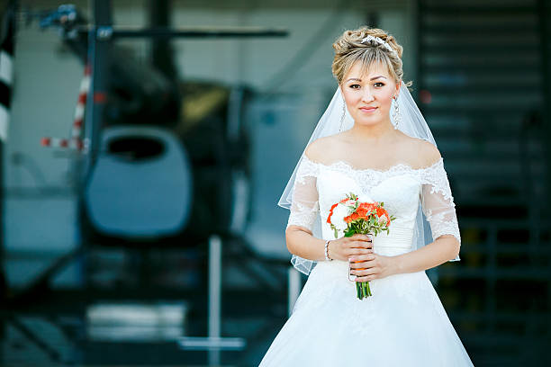 Bride with wedding bouquet on background of helicopter in hangar stock photo