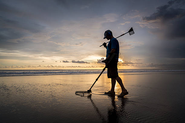 Treasure hunter on the beach with a metal detector stock photo