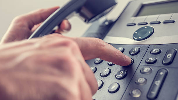 Man dialling out on a landline telephone Man dialling out on a landline telephone pressing the number 6 with his finger on the keypad in a communications concept, close up of his hand and the instrument. With retro filter effect. dialling phone stock pictures, royalty-free photos & images