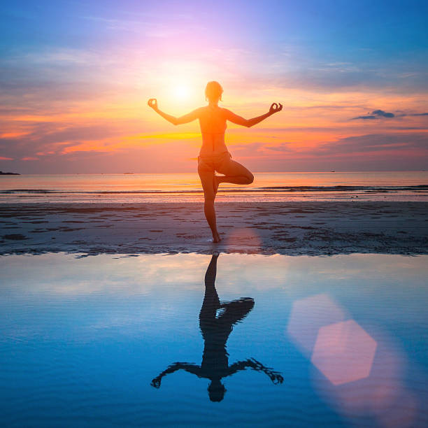 istock Silhouette young female practicing yoga on beach at beautiful sunset. 519252167