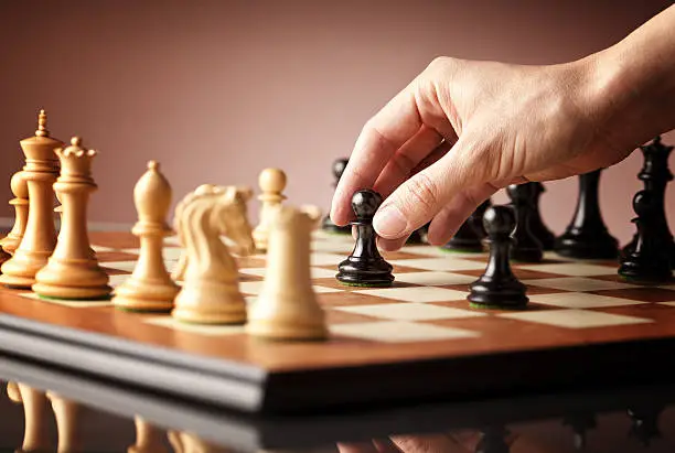 Photo of Playing chess - a hand moving black pawn