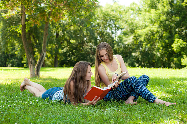 istock Two girls read the book in the park 519262942