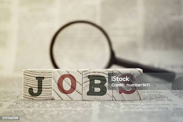 Jobs On Wooden Block And Magnifying Glass On Newspaper Background-foton och fler bilder på Sysselsättning - Människoroller