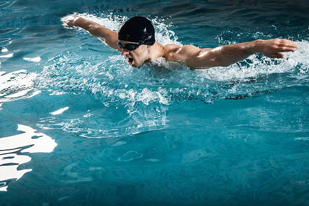 Photo of Muscular young man swims the butterfly