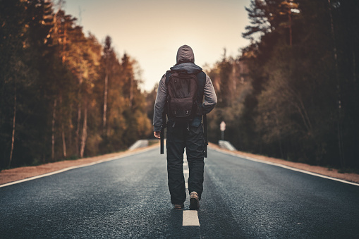 Traveler with backpack walking forward alone. Stock photo.