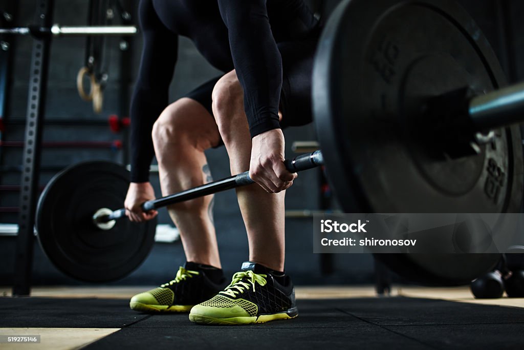 Training with barbell Active young man training with barbell in gym Gym Stock Photo