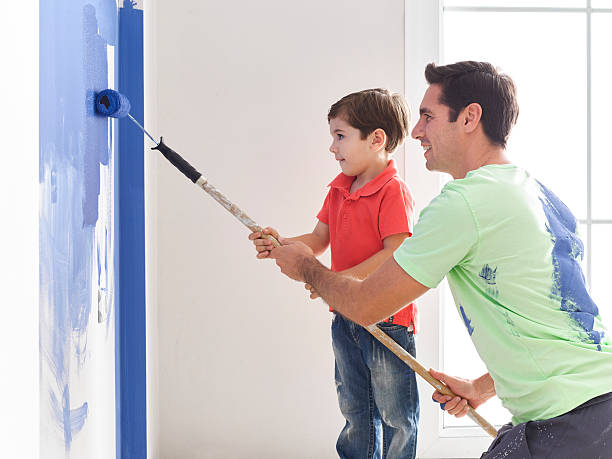 istock Father and son painting wall together 519276338