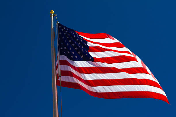 istock Sunlit American Flag Flutters Against Deep Blue Sky 519279313