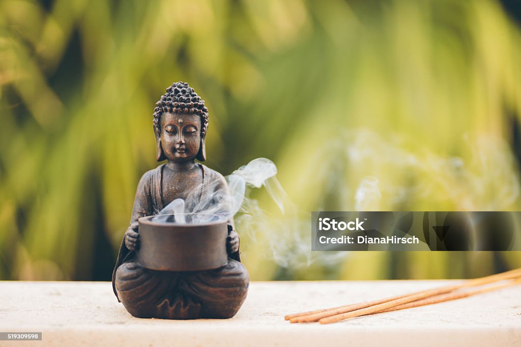 Buddha figurine with incense Buddha figurine with incense, selective focus  Buddha Stock Photo