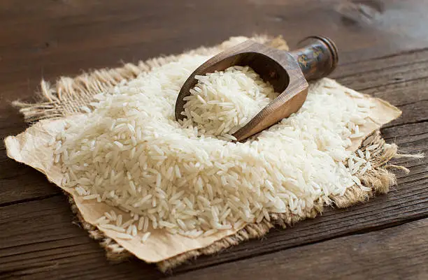 Pile of raw Basmati rice with a spoon close up