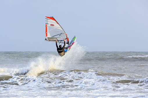 Swansea, UK: February 23, 2016: A windsurfer rides a wave and is airborne. 