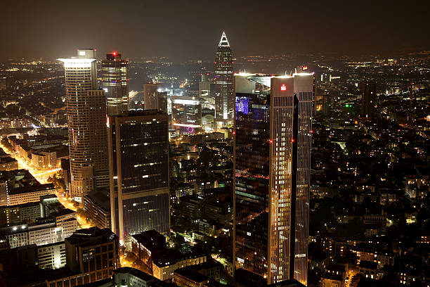 Frankfurt, Germany - October 23, 2011: A wide aerial view over Frankfurt downtown at night, showing the illuminated financial district with the skyline forming skyscrapers of some of the largest Banks in Germany - Deutsche Bank, Volksbank, Sparkasse an Commerzbank. Famous Messetower in the background. Shot was taken from public visitors platform of Maintower about 130 meters above ground.
