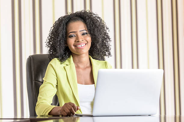 junge büroangestellter mit laptop schaut an die kamera - africa business aboriginal computer stock-fotos und bilder