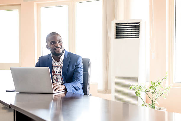 African businessman using laptop looking away, smiling