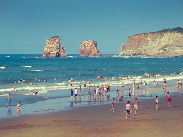 Hendaye, France - August 6, 2015: People on Hendaye beach in France, the Twins rocks in the background