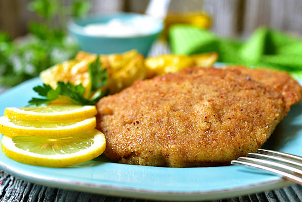 Viennese schnitzel on a blue plate. Viennese schnitzel on a blue plate on rustic background. fried potato stock pictures, royalty-free photos & images
