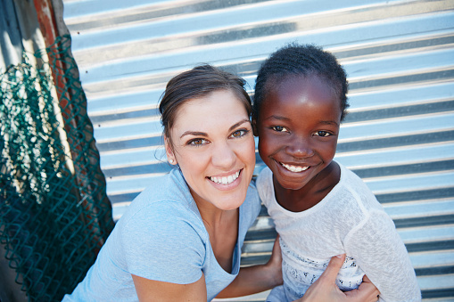 Cropped portrait of a volunteer worker and a young child at a community outreach event