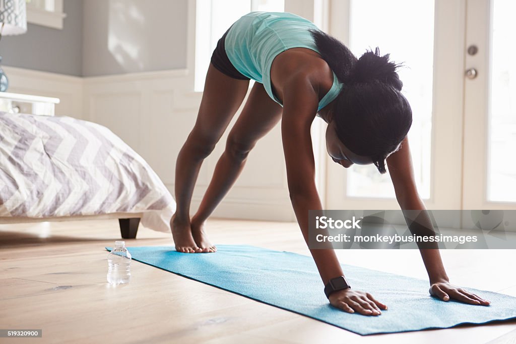 Young black woman in the downward-facing dog yoga pose Bedroom Stock Photo